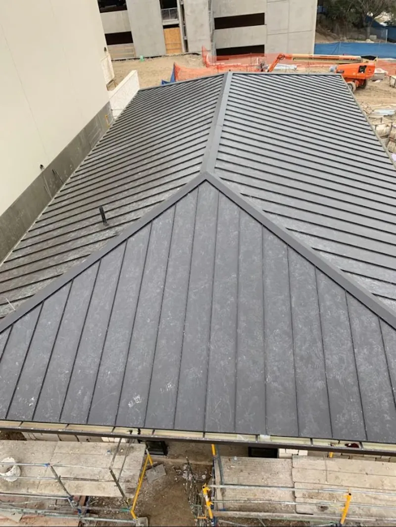 Commercial metal roof construction with crane equipment in Raton